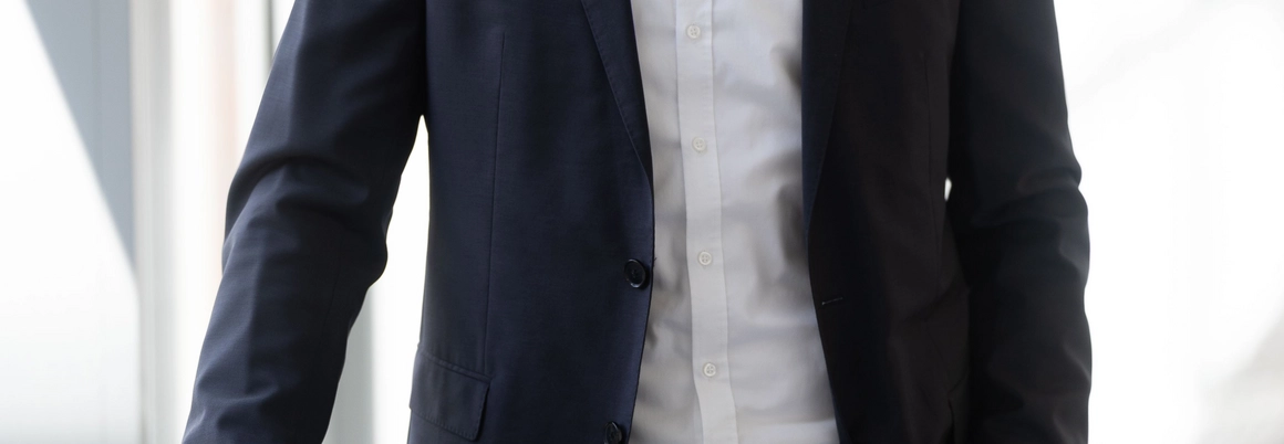 Lächelnder Mensch im Anzug in einem hellen Flur.